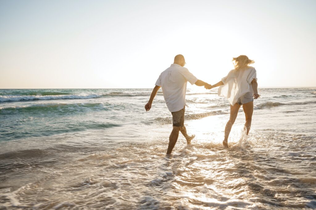 Young beautiful couple walking on beach near sea