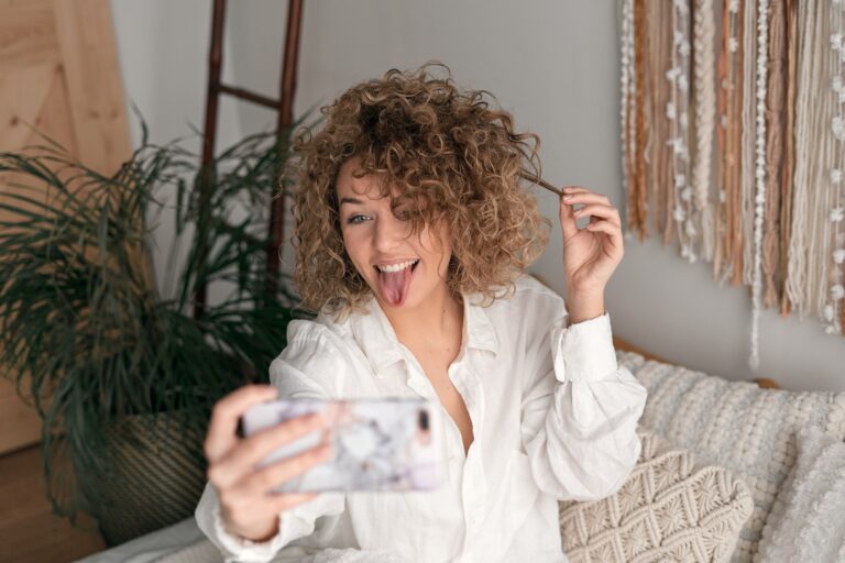 Delighted woman showing tongue and taking self shot at home